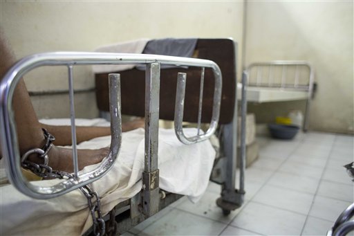 En esta imagen del 12 de mayo de 2016, uno de los cuatro presos encadenados descansa en una sala de urgencias vacía, atendido por parientes y misioneros pero sin personal médico en el hospital de la Universidad Estatal de Haití, en Puerto Príncipe, Haití.