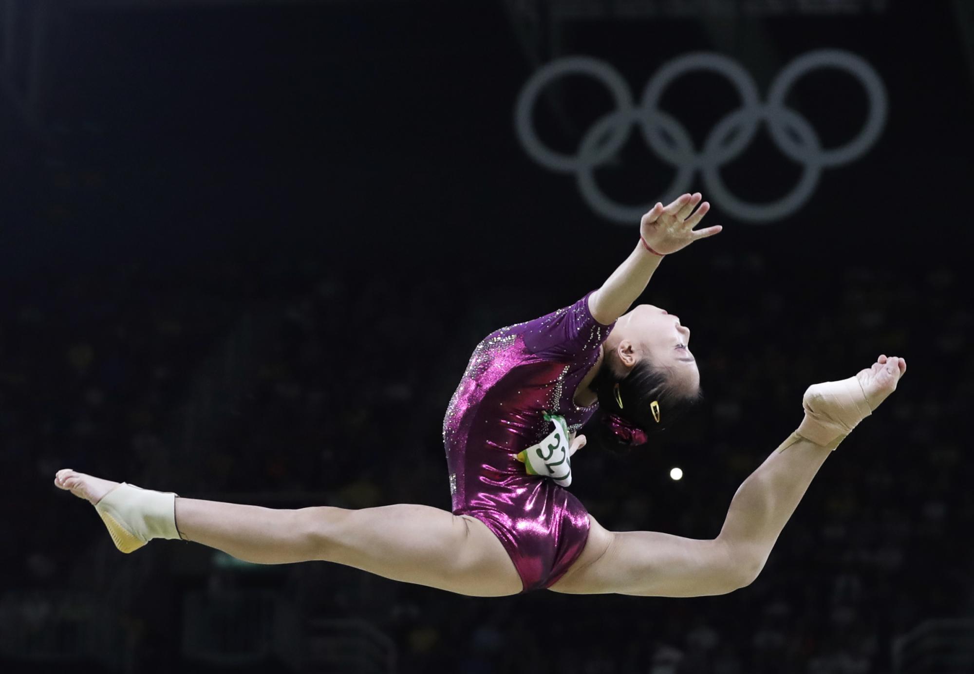 Wang Yan de China en plena ejecución en la barra de equilibro durante la final por equipos de gimnasia artística femenina.