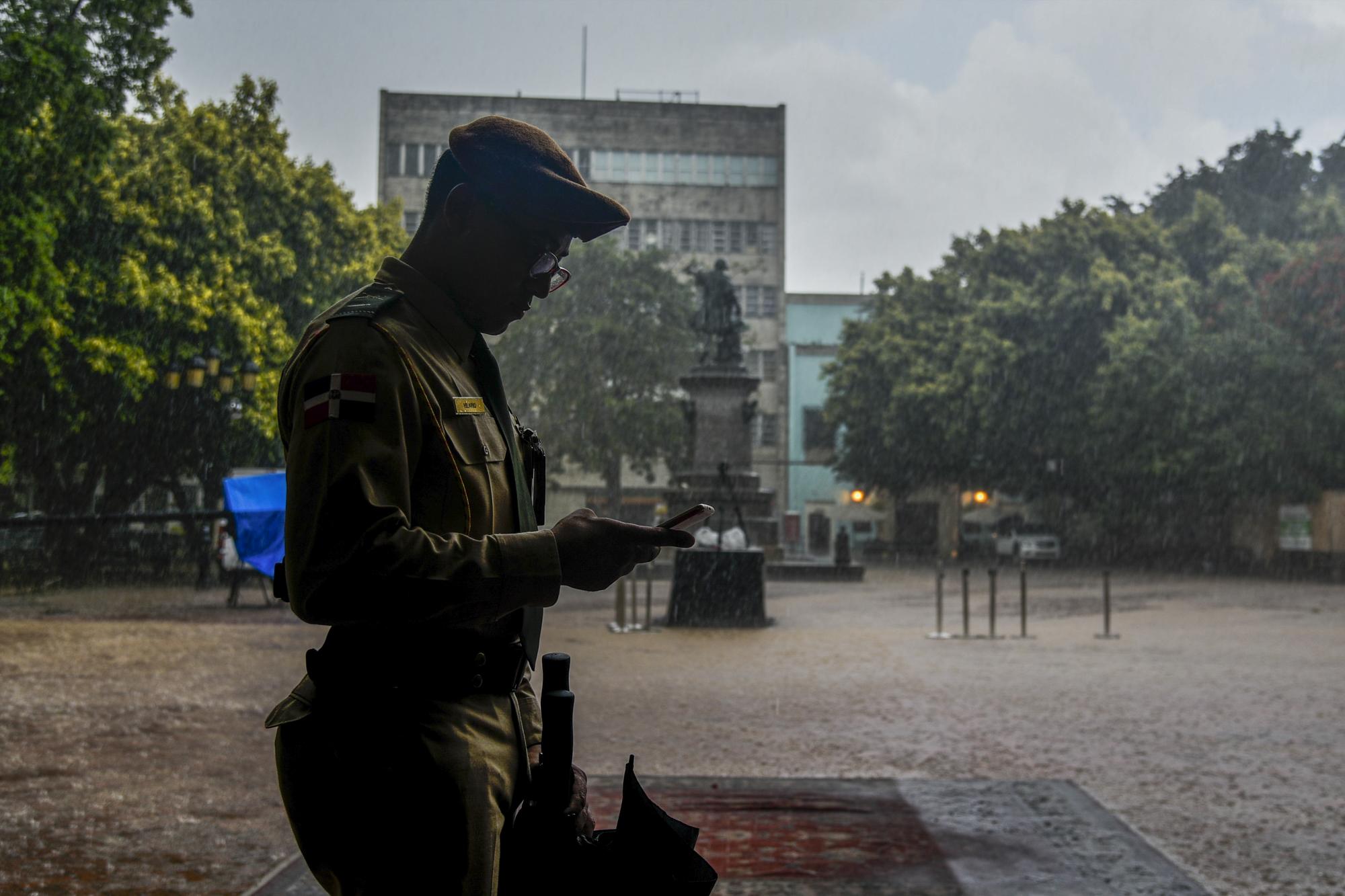 Un oficial del Ejército se resguarda de un fuerte aguacero minutos antes de la llegada del presidente Medina a la Catedral durante las actividades del 16 de Agosto.