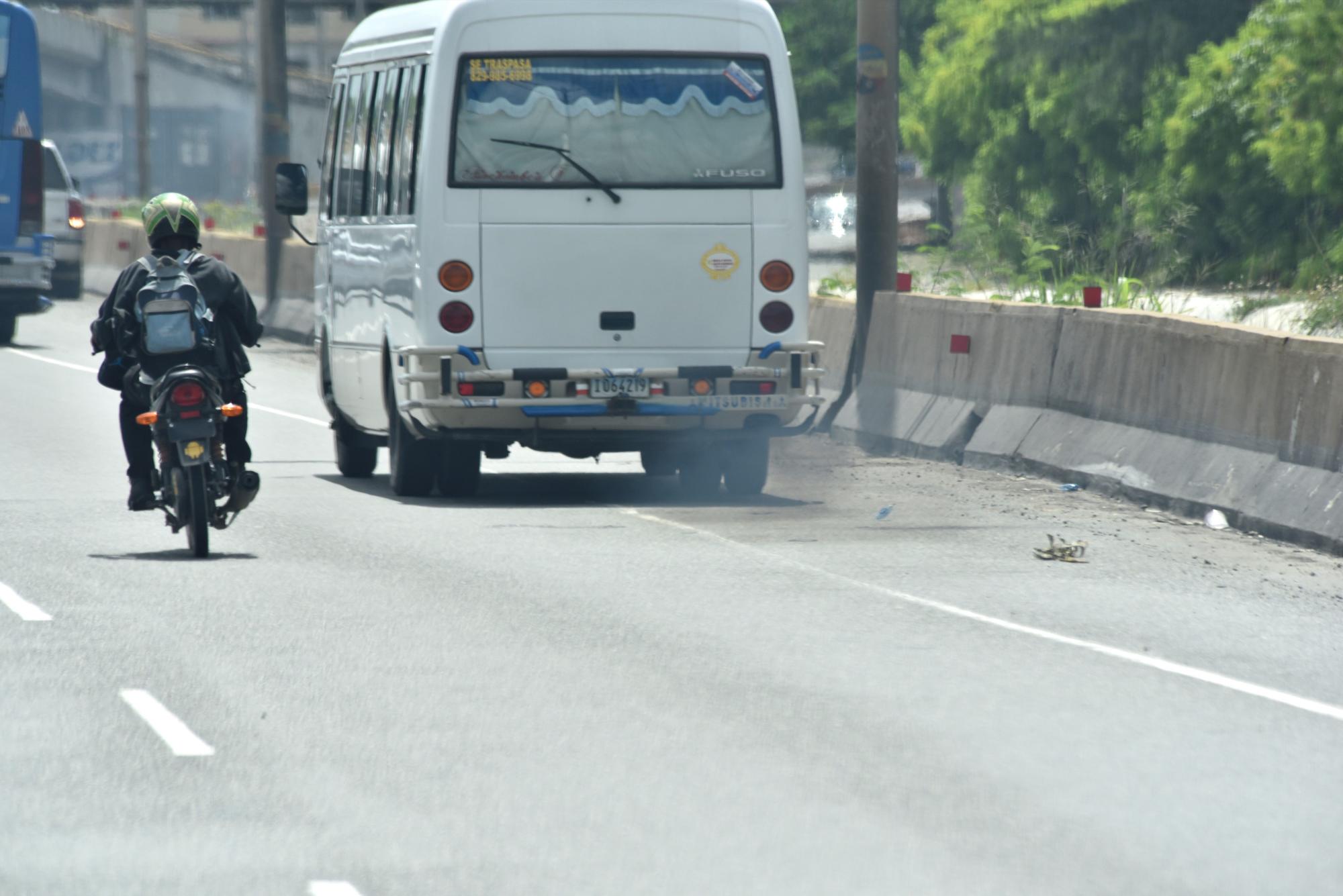 Una guagua de transporte público expide un humo negro por el tubo de escape.