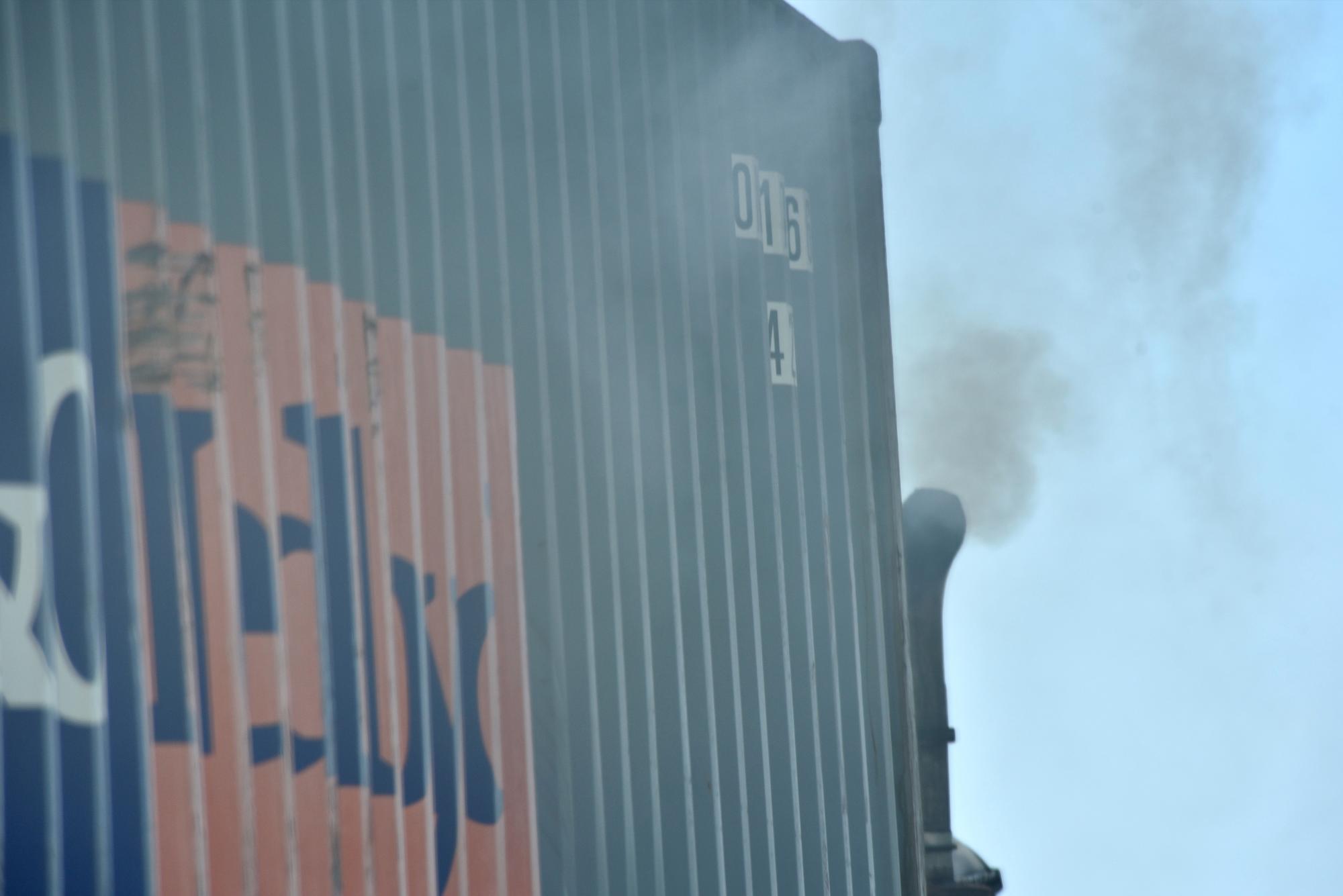 Un camión bota humo por el tubo de escape mientras transita por la ciudad.