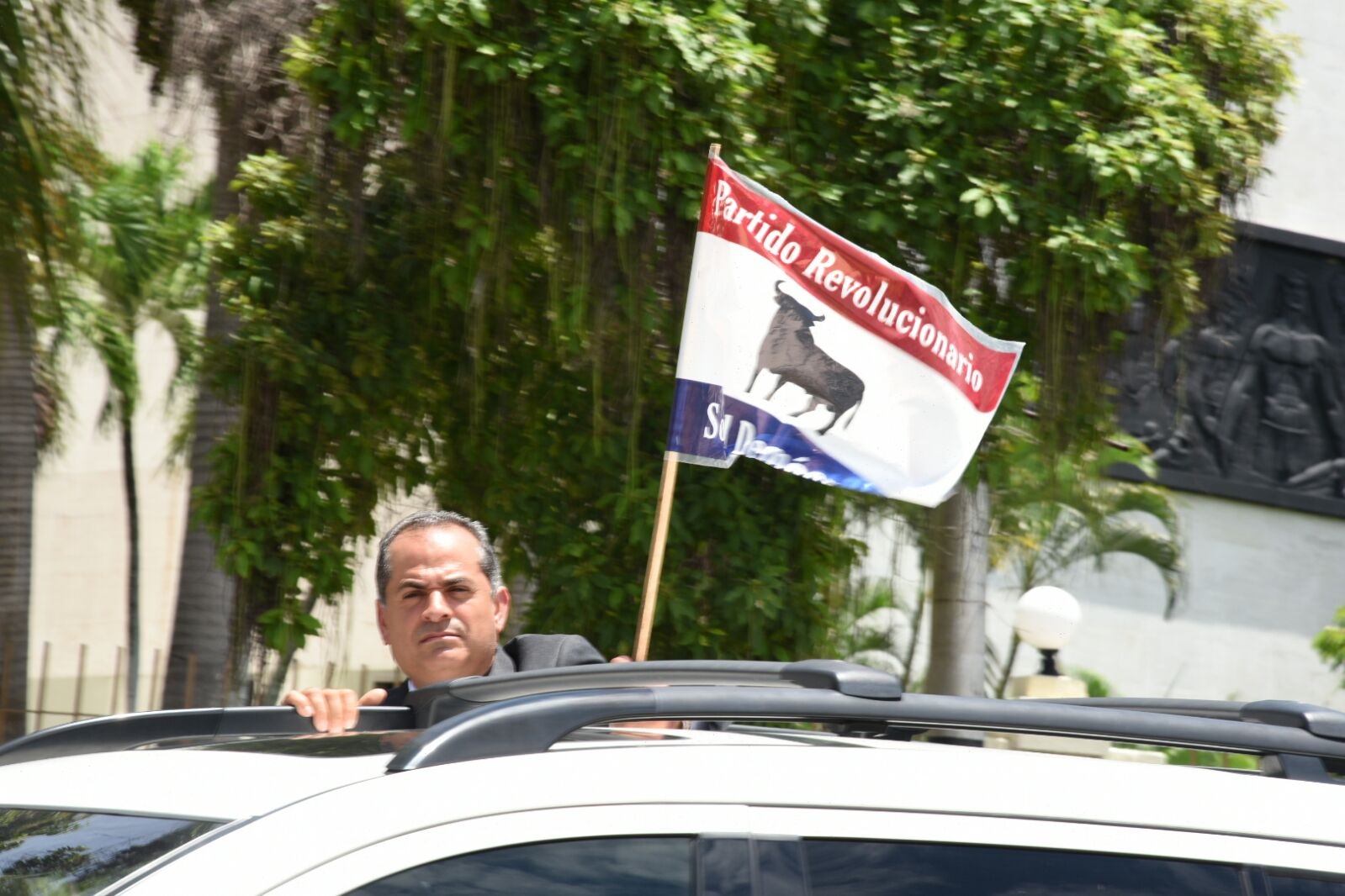 Un dirigente del Partido Revolucionario Social Demócrata (PRSD) sostiene la bandera de esa organización política durante el recorrido del féretro con los restos de Hatuey De Camps