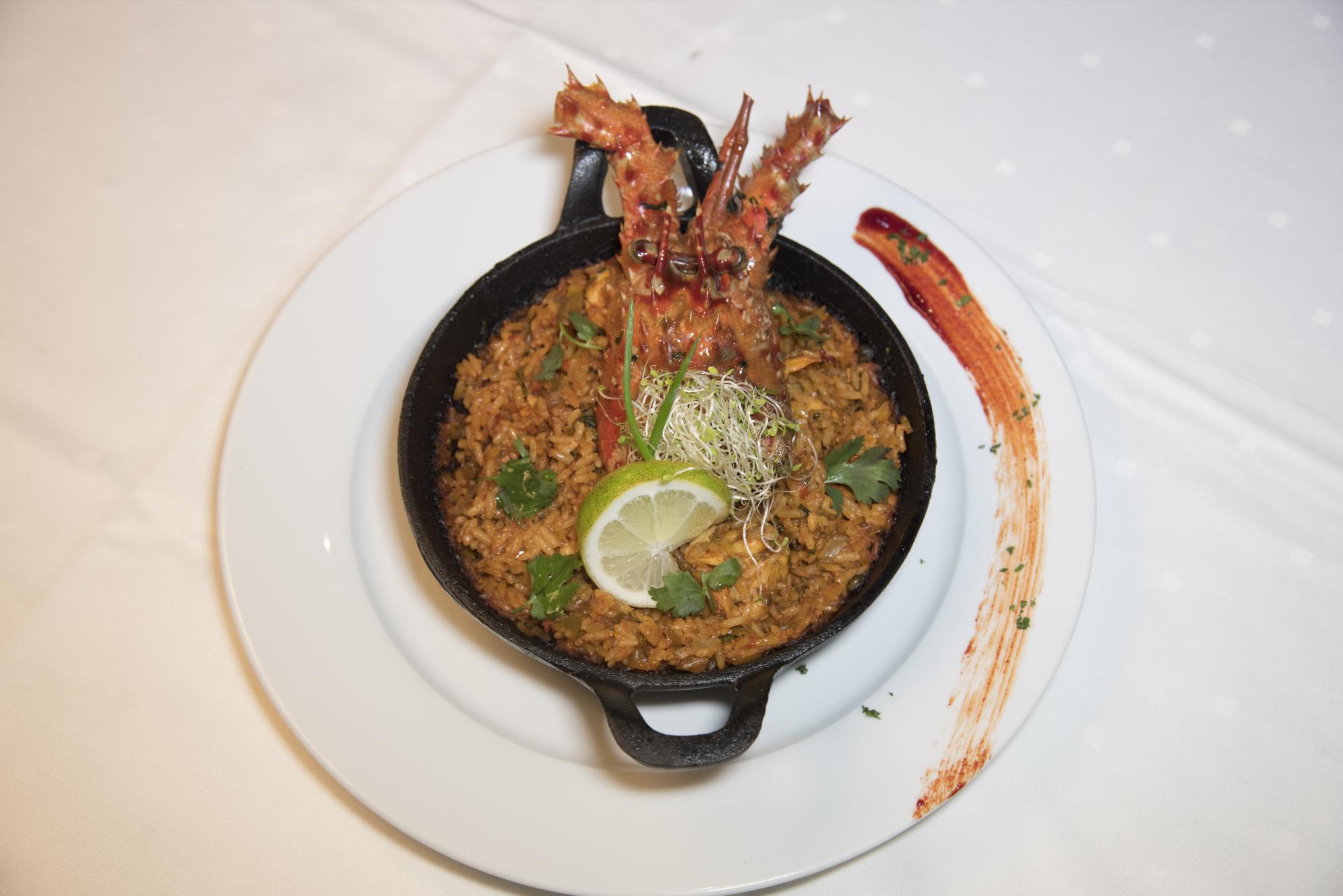 Locrio de langosta. Tradicional locrio criollo a base de langosta, con una guarnición de fritos verdes.