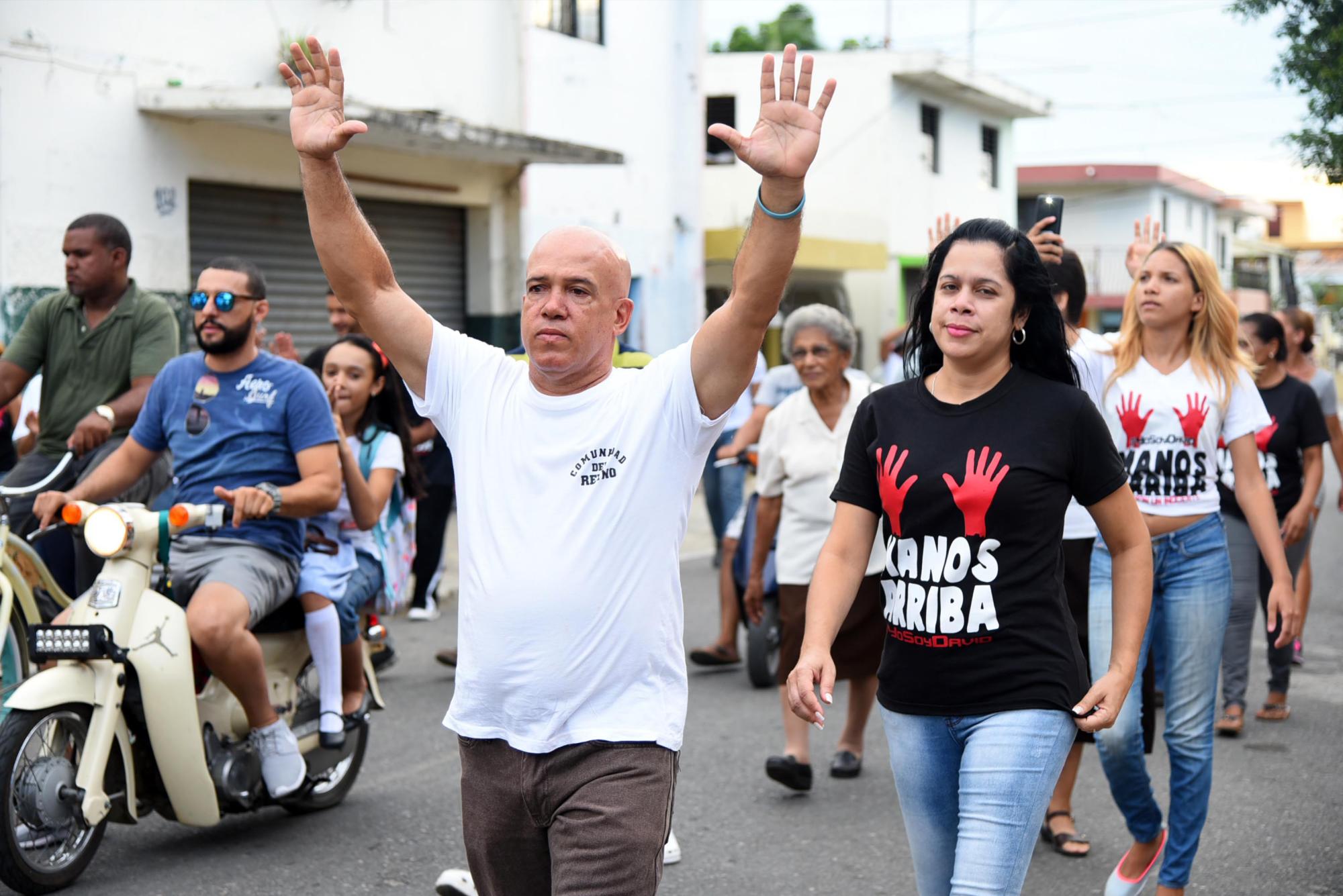 Un señor levanta sus brazos en protesta por la muerte del joven.