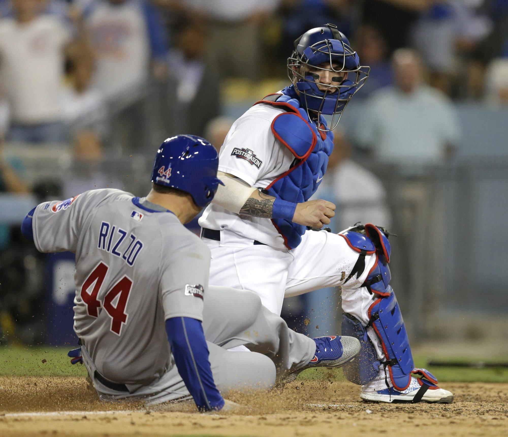Anthony Rizzo (i) de Cachorros anota ante Yasmani Grandal (d) el 19 de octubre de 2016, durante un juego de la Liga Nacional de la MLB en el estadio Dodger de Los Ángeles, California. 