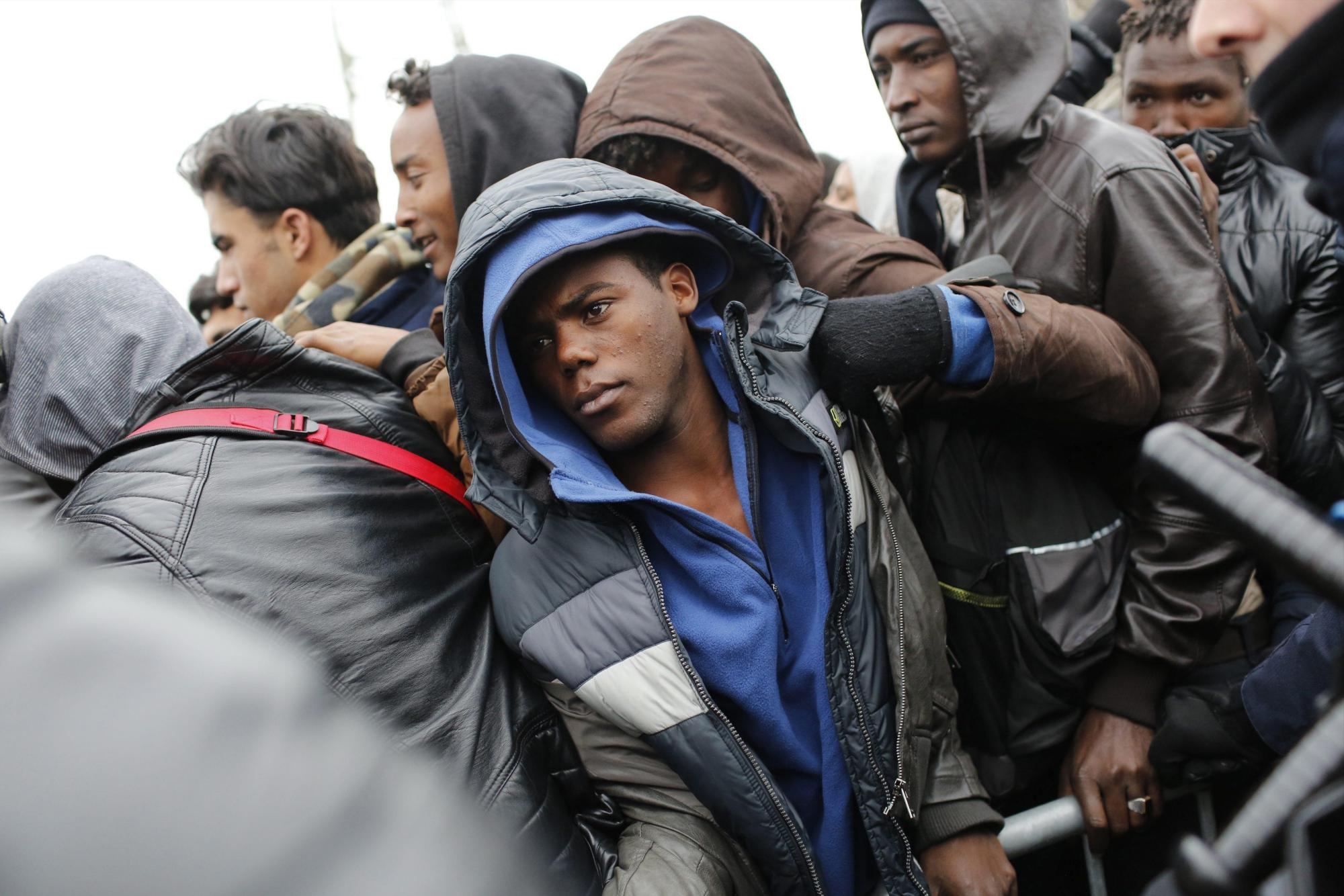 Varios migrantes esperan para poder tomar un autobús cerca del campamento conocido como La Jungla durante su desmantelamiento en Calais (Francia) hoy, 24 de octubre de 2016.