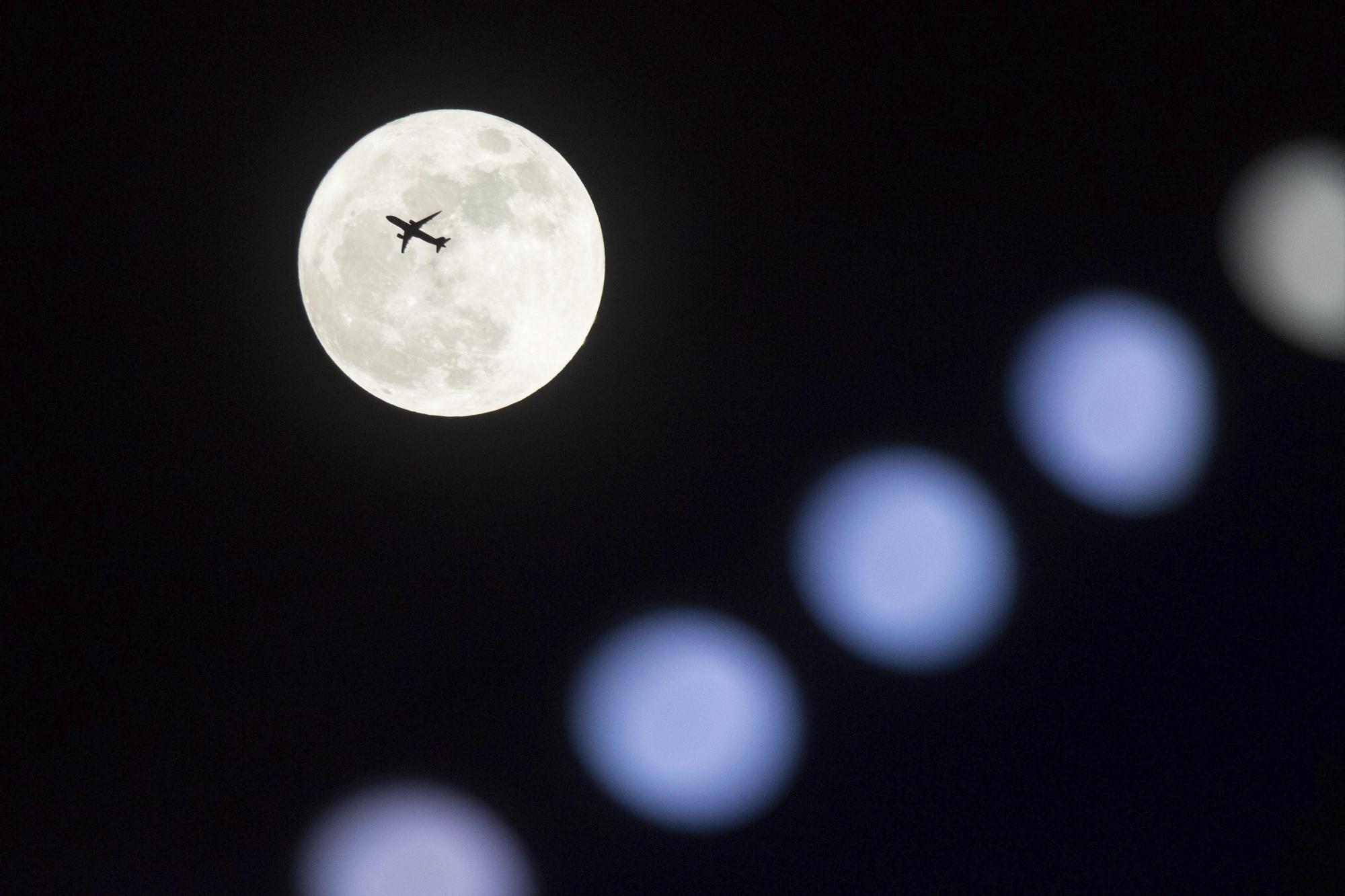 Un avión vuela frente a la superluna en Hong Kong (China).