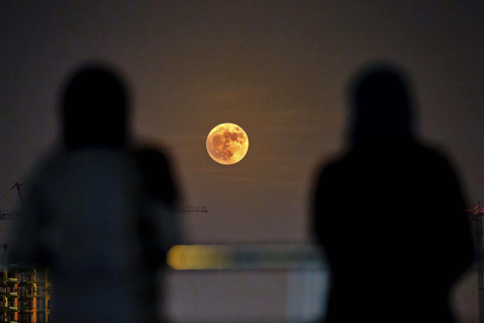 Dos mujeres observan la superluna sobre Teherán, Irán.