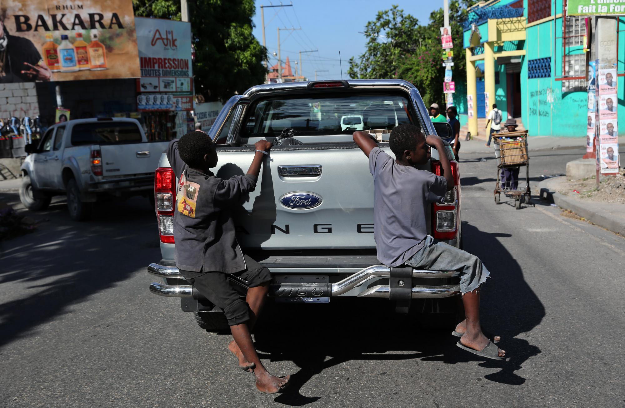 Dos niños viajan de incógnito en una camioneta en Puerto Príncipe.