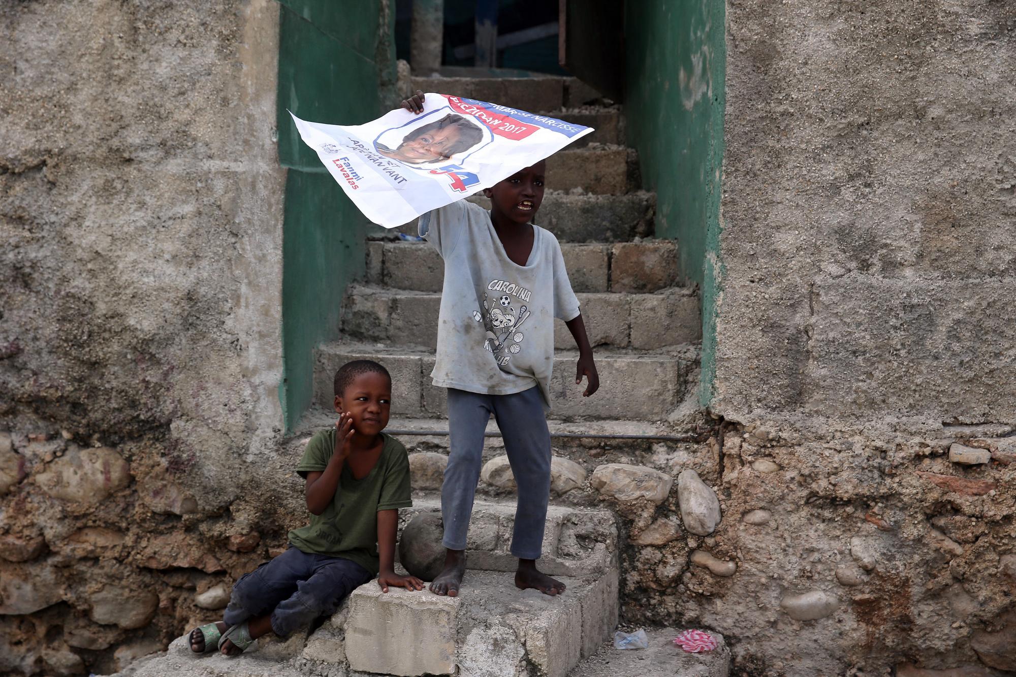 Dos niños con una pancarta de la candidata Maryse Narcisse.