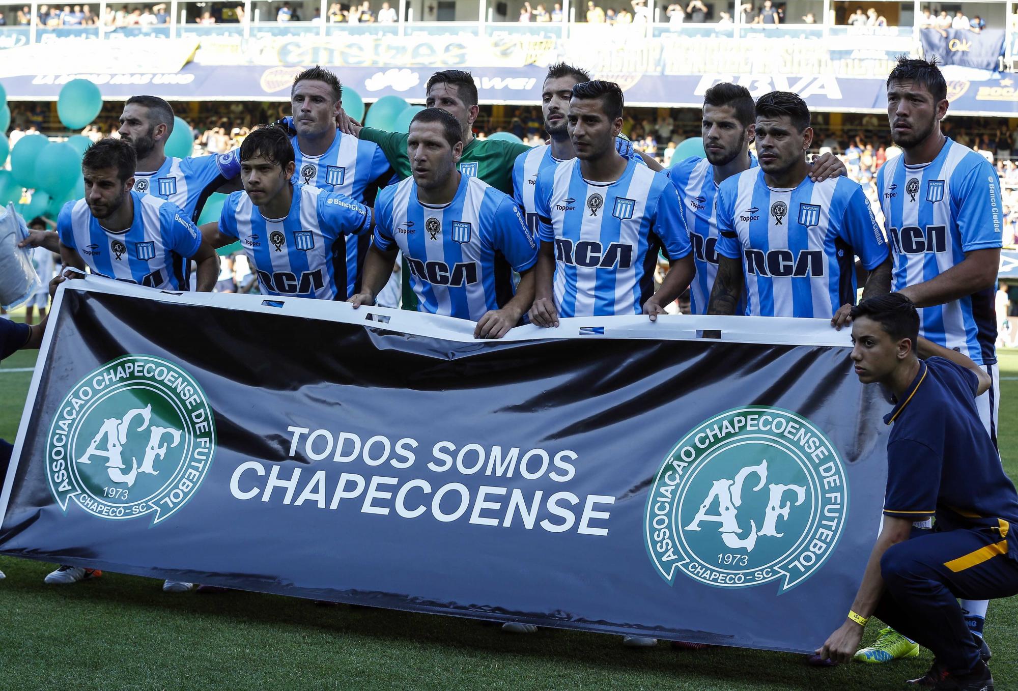 Jugadores del Racing Club, de la liga de Argentina, posan con una letrero que recuerda al Chapecoense, antes del encuentro liguero contra el Boca Juniors. 