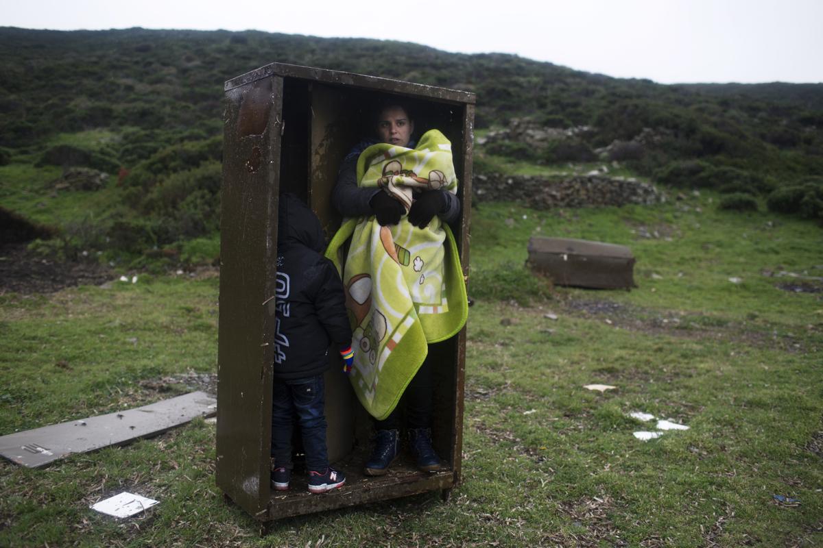 El 20 de enero una mujer se refugia de la lluvia, junto a sus hijos, luego de llegar a la isla griega de Pasas desde Turquía.