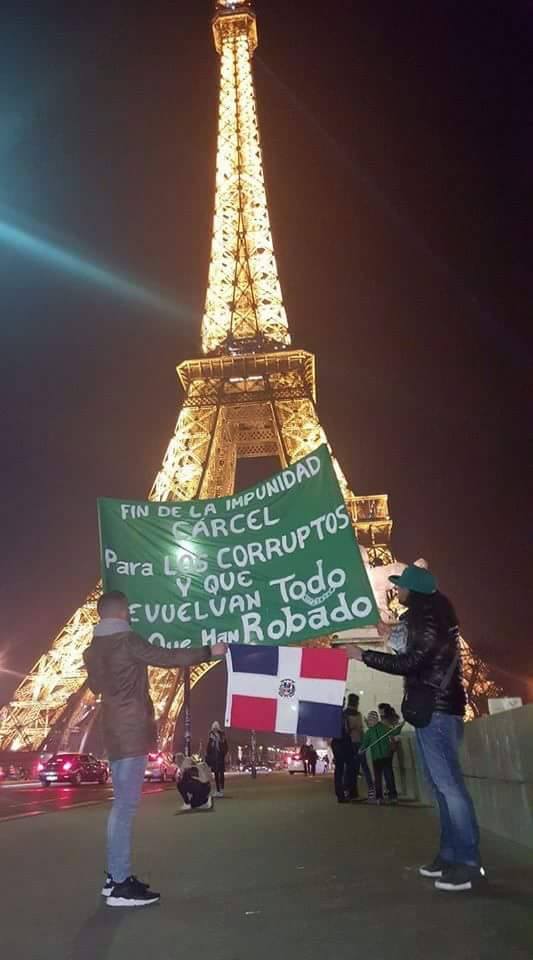 Dos jóvenes sostienen un cartel frente a la Torre Eiffel de la ciudad de París, Francia, que dice: “No a la impunidad, cárcel a los corruptos y que devuelvan todo lo que han robado”.