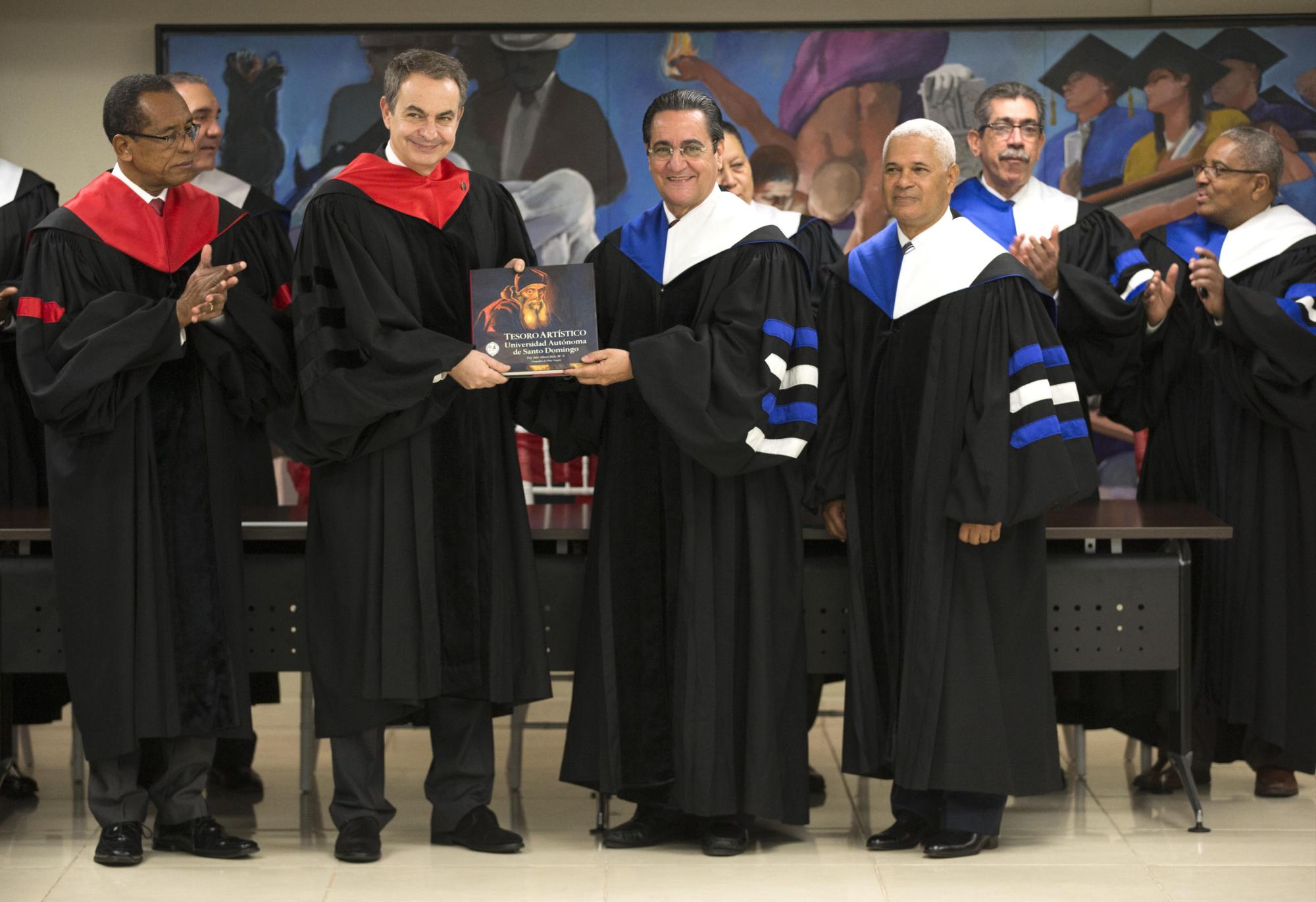 El expresidente del gobierno español, José Luis Rodríguez Zapatero (segundo a la izquierda), recibe un regalo del rector de la Universidad Autónoma de Santo Domingo (USAD) Iván Grullón (al centro), luego de recibir un doctorado Honoris Causa de la USAD, en Santo Domingo.