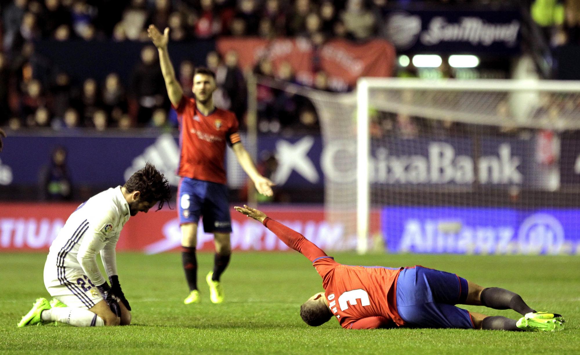 El jugador de Osasuna Tano (d) se lesiona ante Isco (i), del Real Madrid, durante el partido de Liga en Primera División disputado esta noche en el estadio de El Sadar, en Pamplona.