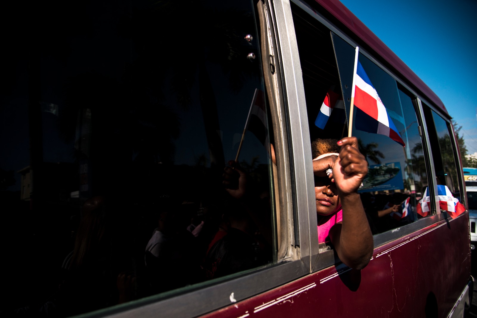 Mujer en una guagua portando la Bandera dominicana.