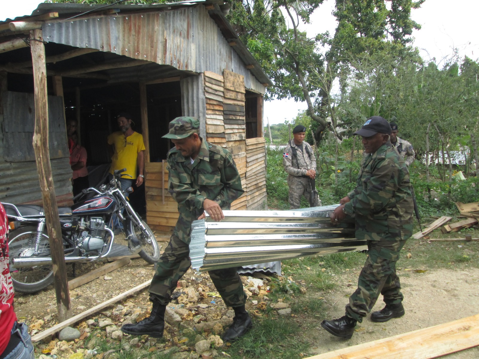 Militares cargan hoja de zinc nueva para vivienda en reparación. 