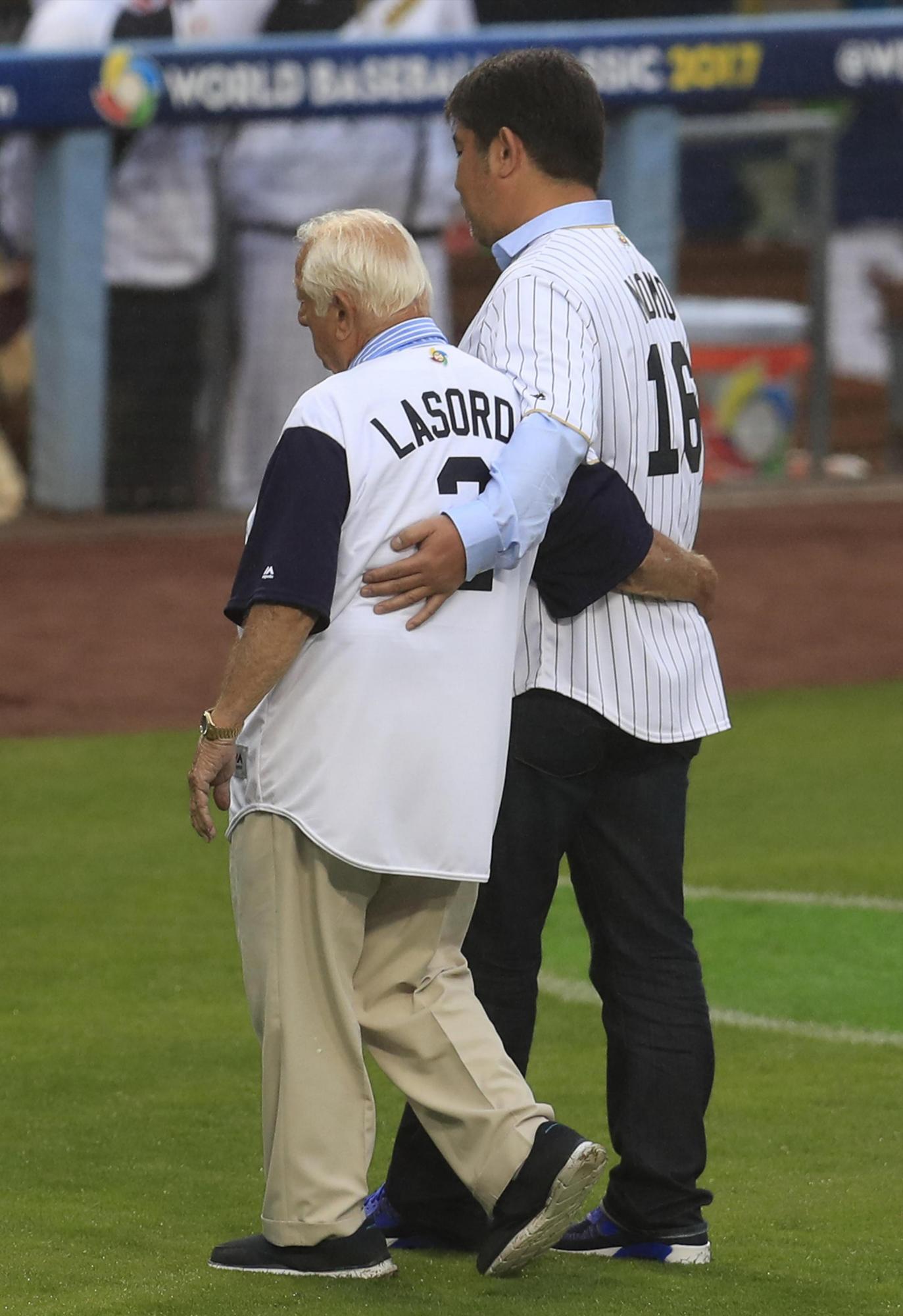 El exlanzador japonés Hideo Nomo (d) y el extécnico de Los Dodgers Tommy Lasorda (i) salen luego de hacer el lanzamiento de honor previo al partido Japón-EE, el  martes 21 de marzo de 2017.