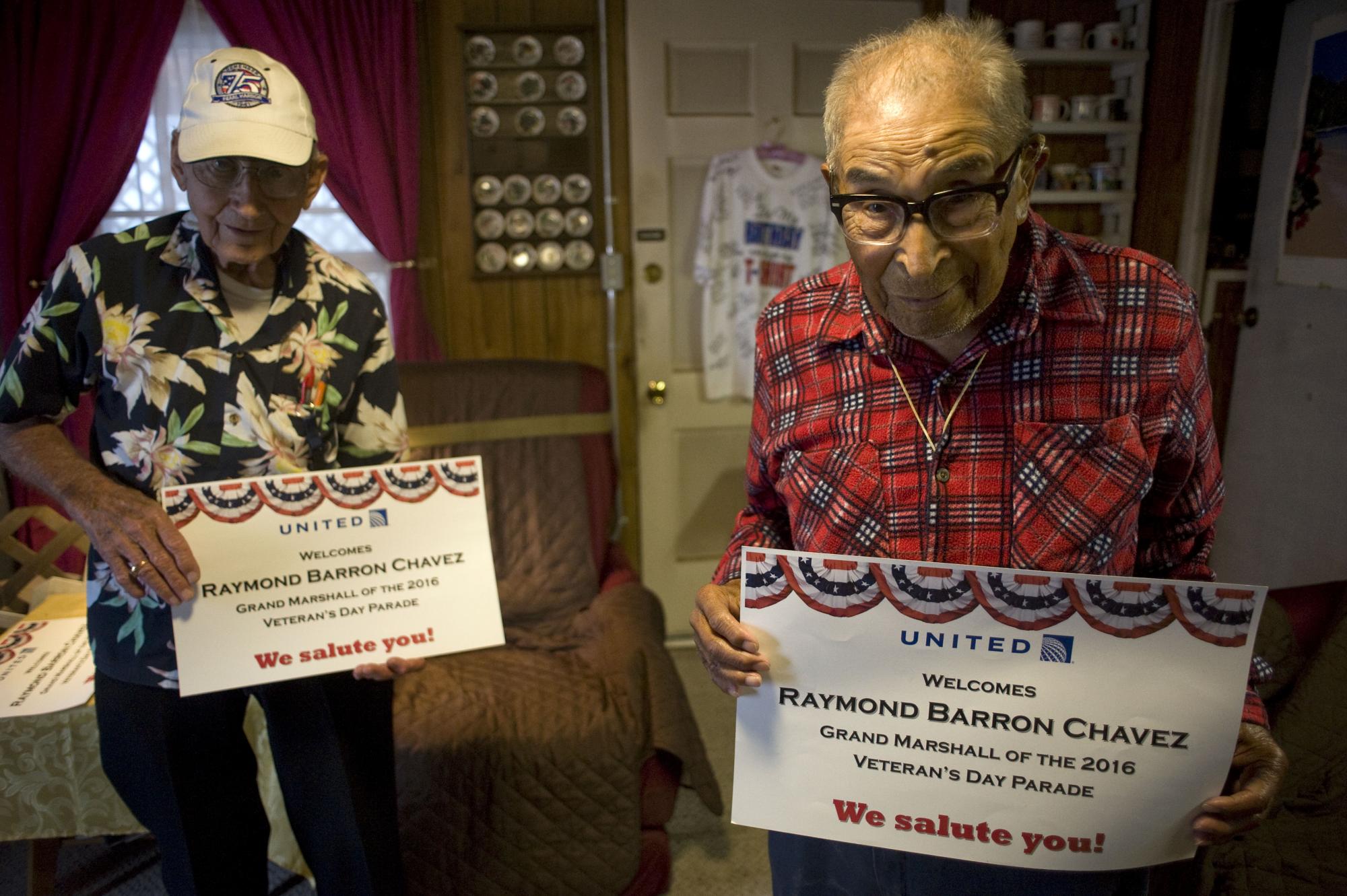Ray Chavez, de 105 años, el sobreviviente más longevo del ataque a Pearl Harbor (d), posa para EFE en su casa de Poway, cerca de San Diego (California), junto a su amigo y también veterano Stu Hedley, de 95 años, enseñando los posters con sus nombres que usaron para el último desfile de veteranos. 