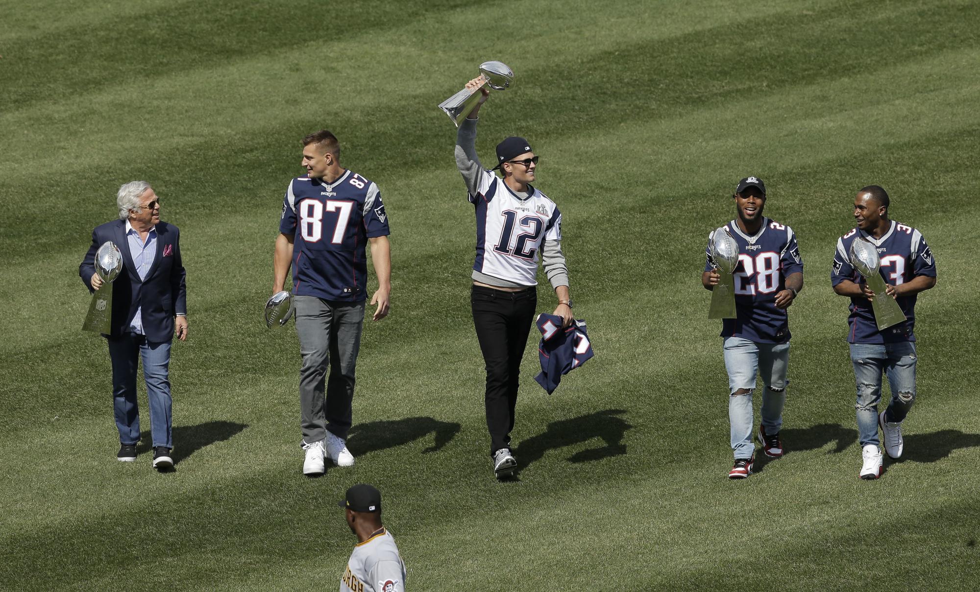 Miembros de los Patriots, desde la izquierda, Robert Kraft, propietario, y los jugadores Rob Gronkowski, Tom Brady, James White y Dion Lewis, llevando el trofeo del Super Bowl antes del partido entre Piratas y Medias Rojas el 3 de abril.