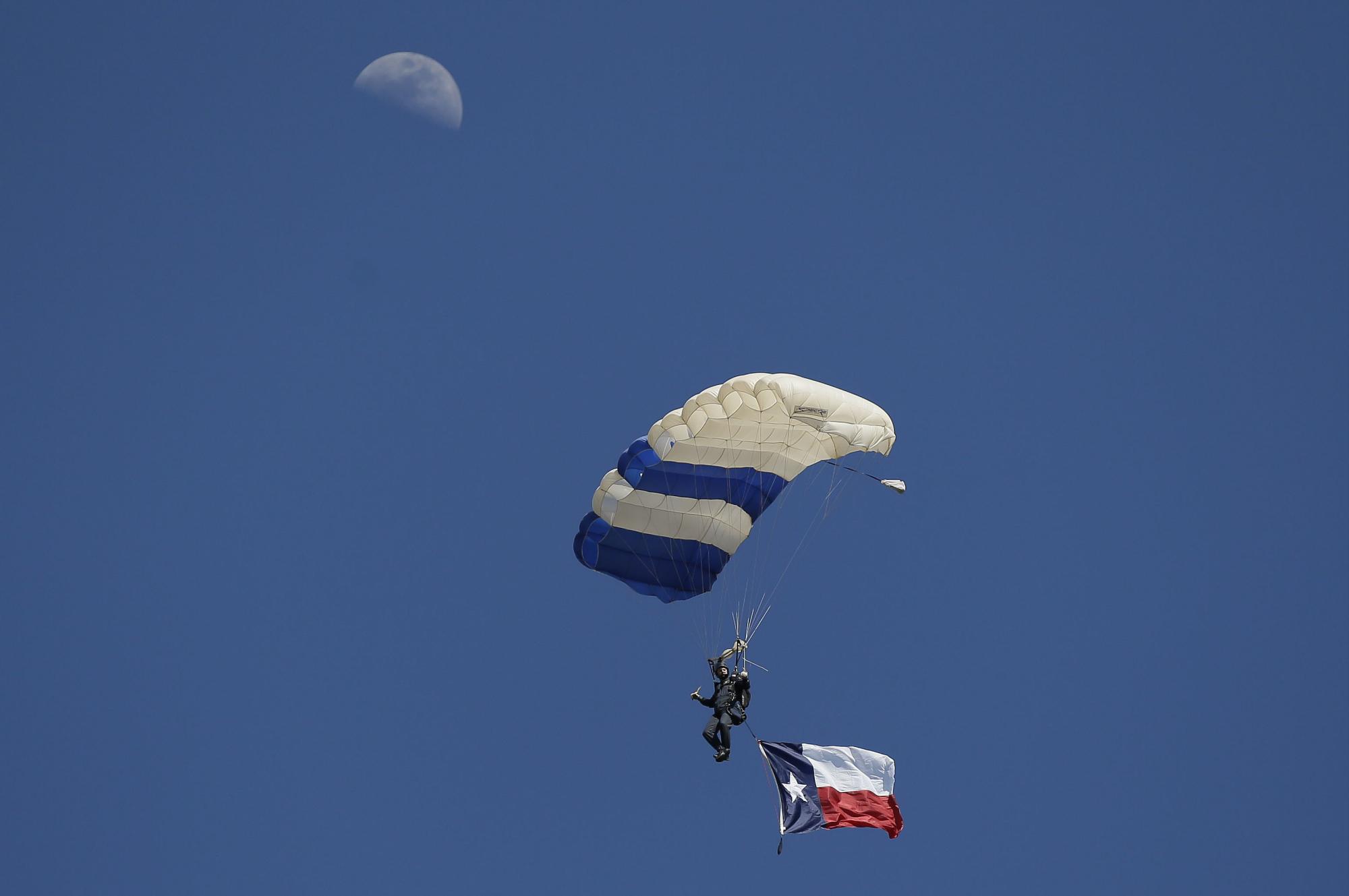 Un paracaídas vuela con la bandera de Texas en la ceremonia de apertura antecediendo el encuentro entre los Indios de Cleveland y los Vigilantes de Texas, en Arlington, el pasado lunes 3 de abril.