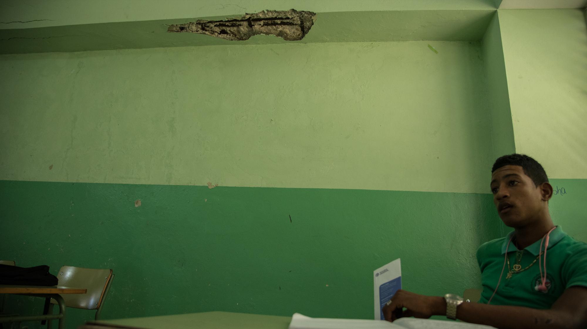 Un estudiante está sentado próximo a donde se desprendió un pedazo de concreto del techo en el Liceo Federico Henríquez y Cavajal.