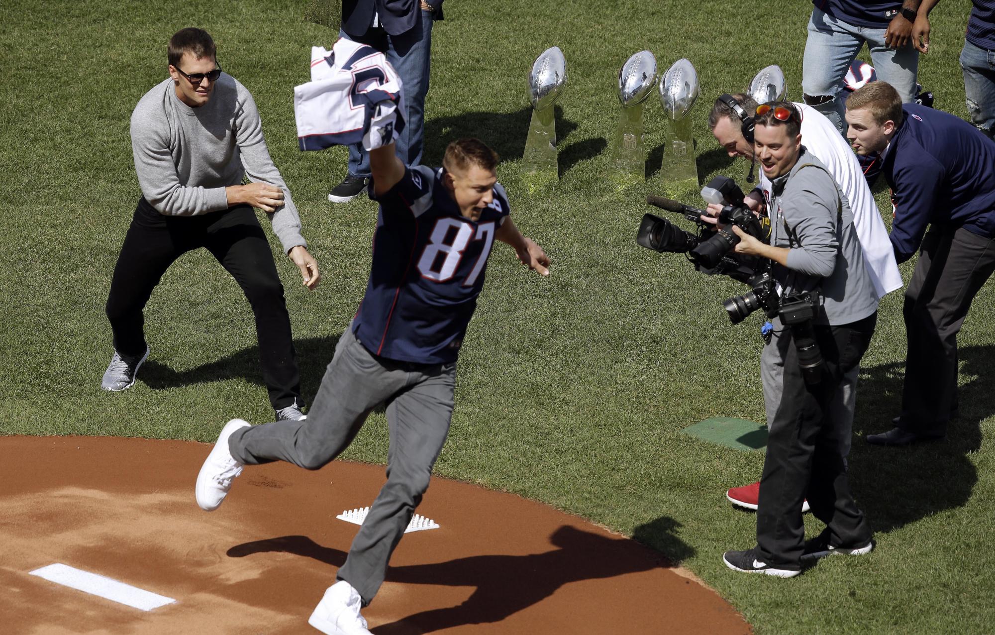 Rob Gronkowski, derecha, corre con la camiseta que le fue robada durante el Super Bowl a Tom Brady, una broma ocurrida antes del juego de apertura entre Piratas y Medias Rojas. Los Patriots le ganaron el Super Bowl en febrero a los Falcons de Atlanta Falcons, en Houston.