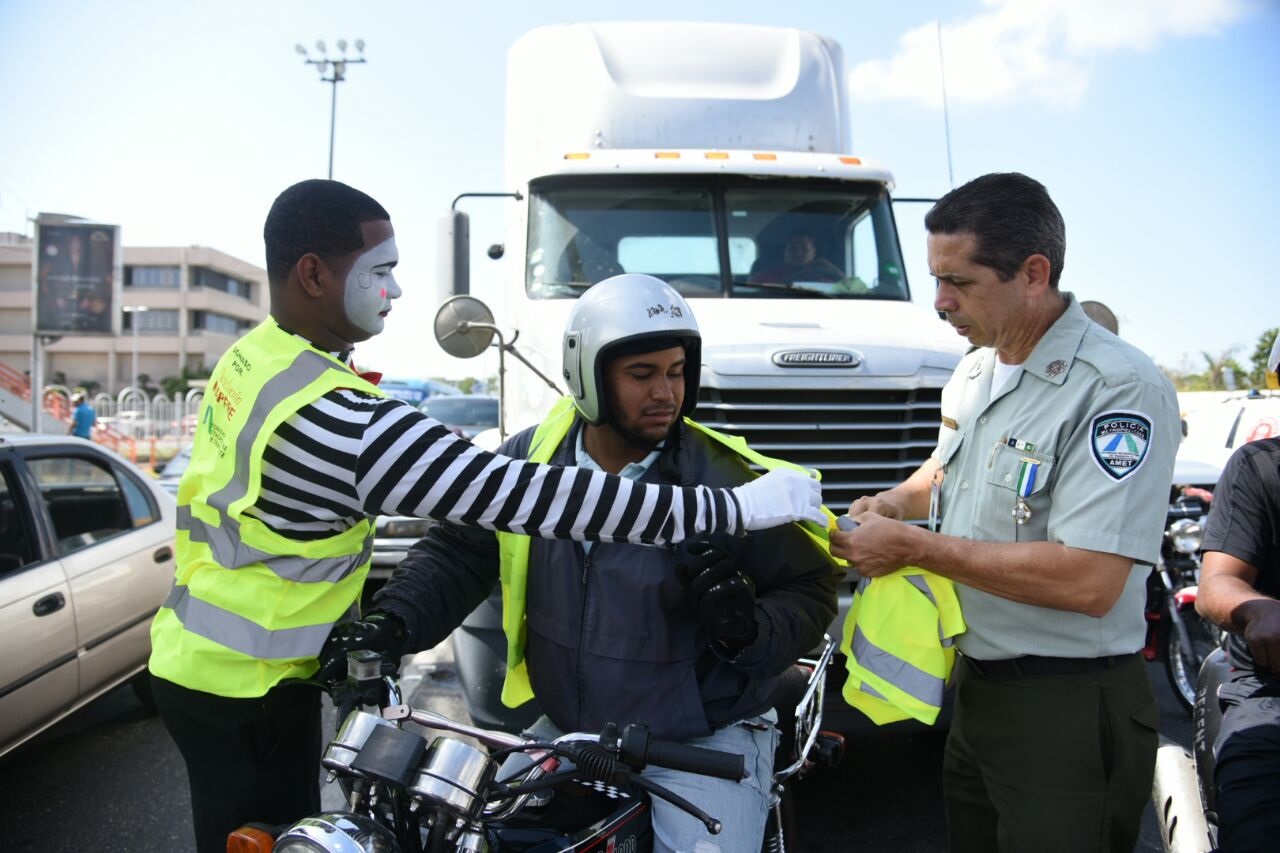 El vocero de la AMET, Diego Pesqueira, coloca un chaleco a un motociclista en la intersección de la avenida John F. Kennedy con Máximo Gómez.