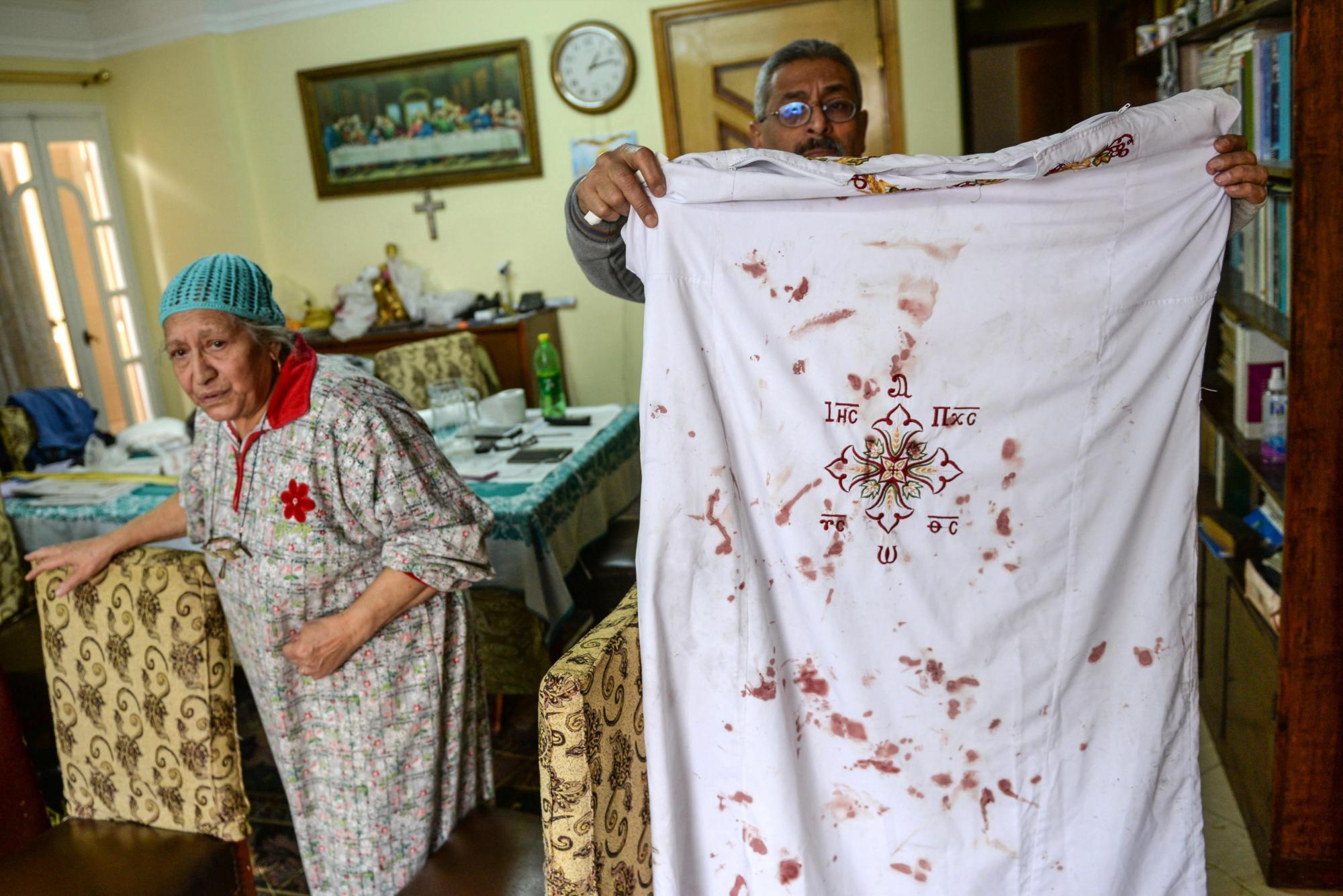 Un hombre sostiene ropa de un clérigo copto con sangre.