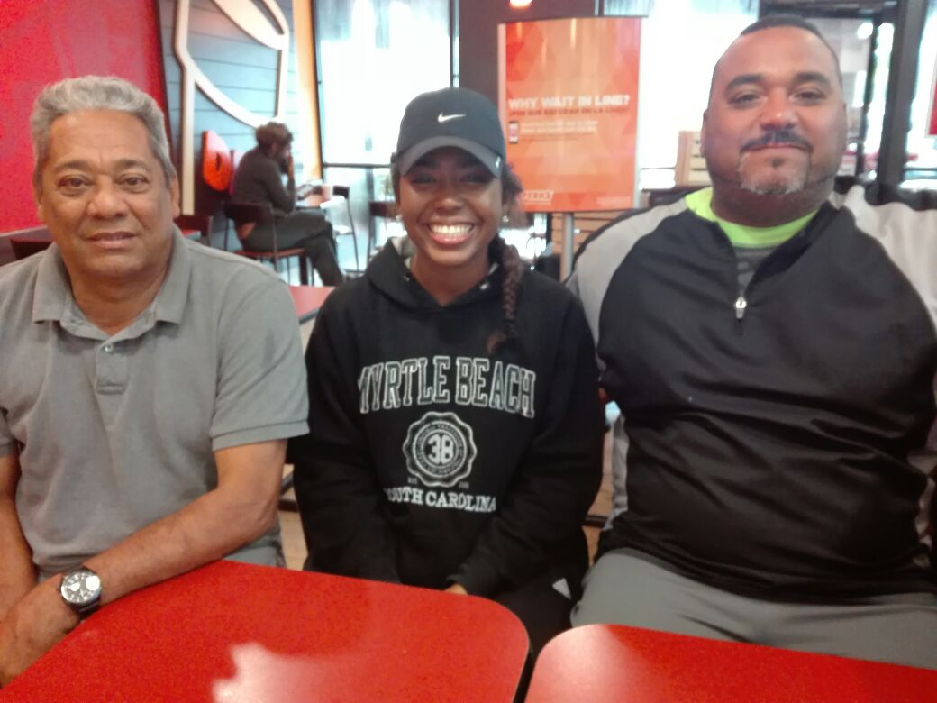 Daniela Bautista (centro) junto a José Pascual (izquierda) y su hijo Delvin, quien dirige la academia de la Federación Dominicana de Sóftbol en La Florida.