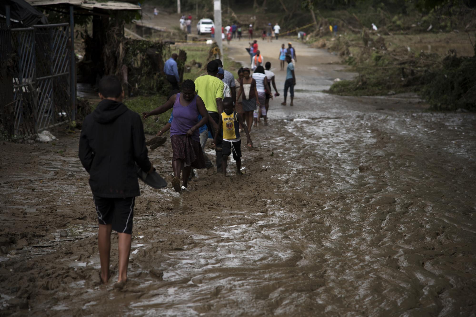 Un grupo de personas camina entre el lodo provocado por las lluvias en San Cristóbal.