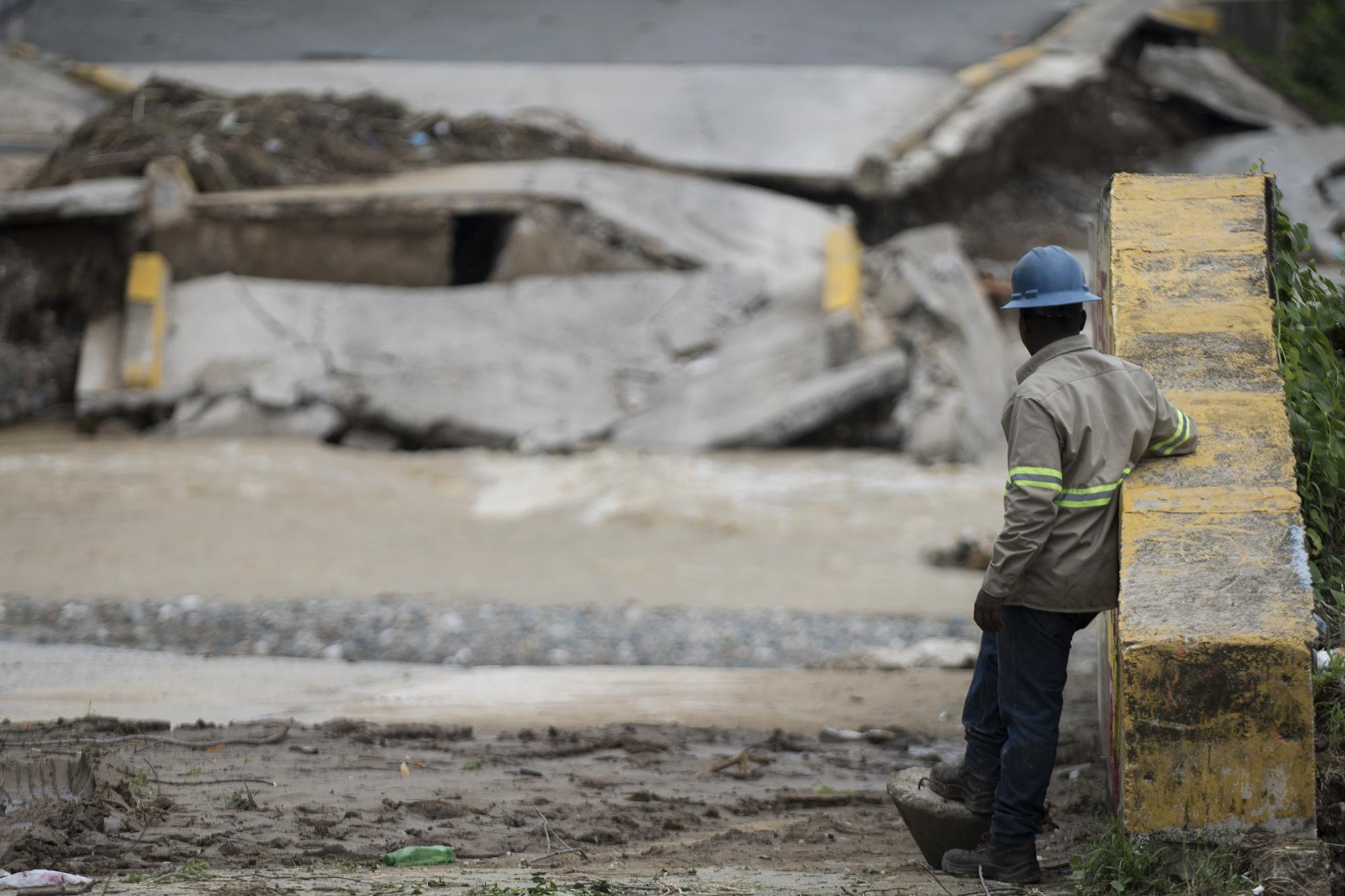 Un brigadista mira un puente colapsado por las lluvias en San Cristóbal.
