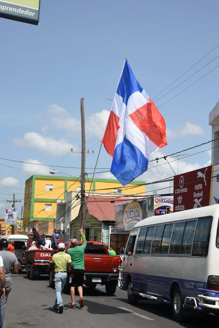 Un manifestante ondea la bandera nacional por una calle de Azua.