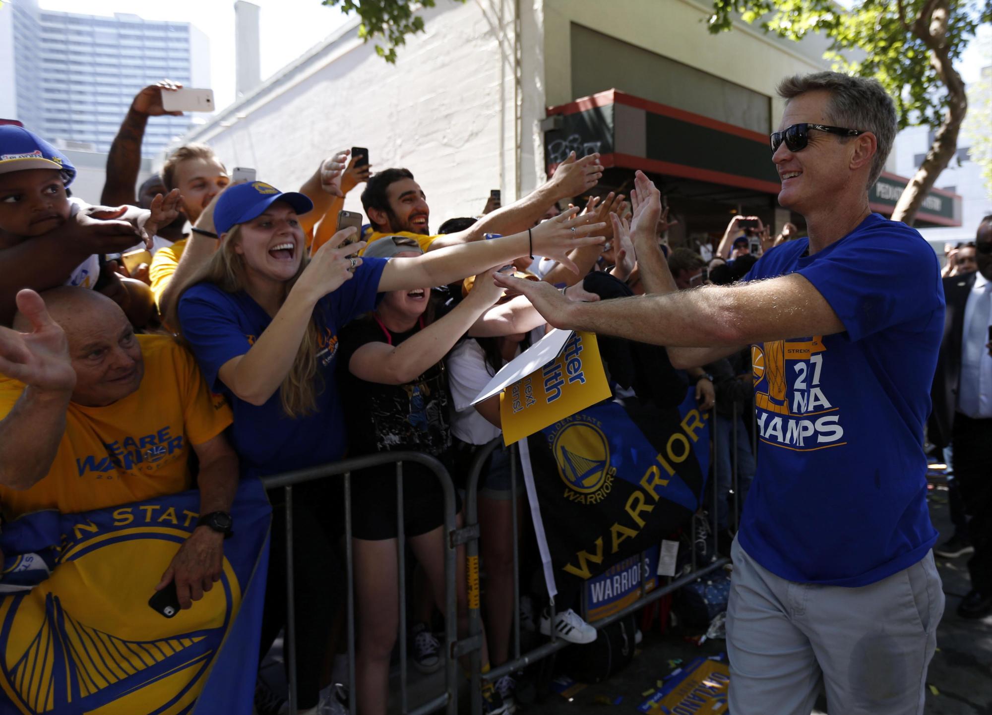 El entrenador de Golden State Warriors Steve Kerr (d) saluda a aficionados durante el Desfile de los Campeones de la NBA.