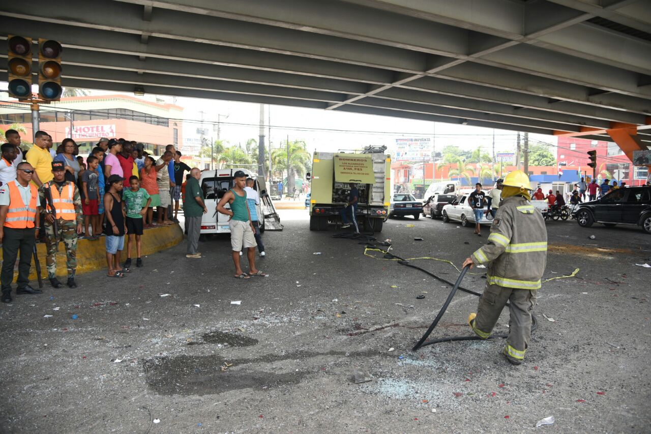 Bomberos despejan la calle luego del accidente ocurrido hoy, 11 de julio de 2017, en Los Alcarrizos.