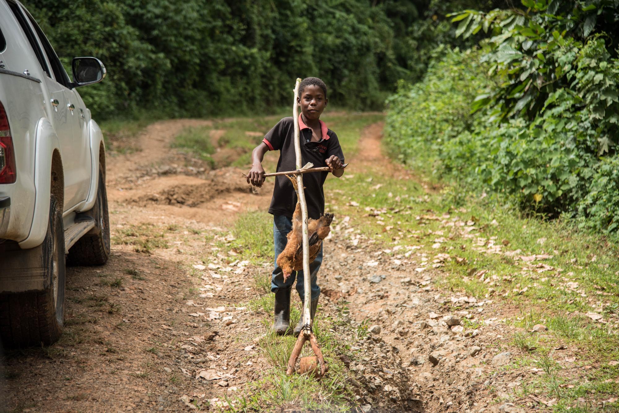 Un niño juega a la orilla de la carretera con un juguete improvisado.