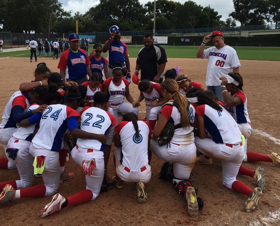 El equipo dominicano en oración después del partido en que venció a Argentina en su debut en el torneo mundial sub-19 de sóftbol femenino que se celebra en La Florida.