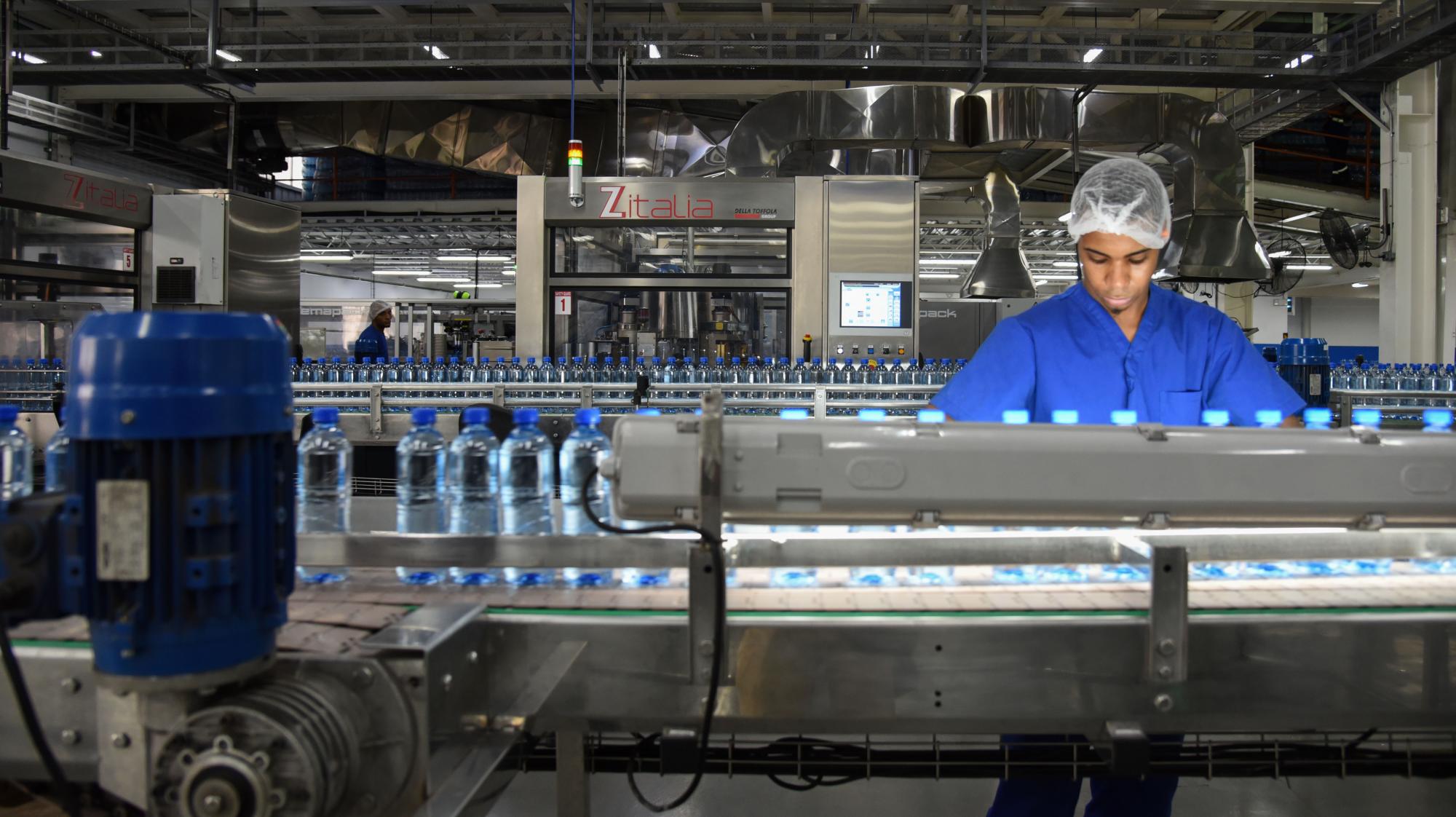 Un operador inspecciona las botellas que pasan por la máquina.