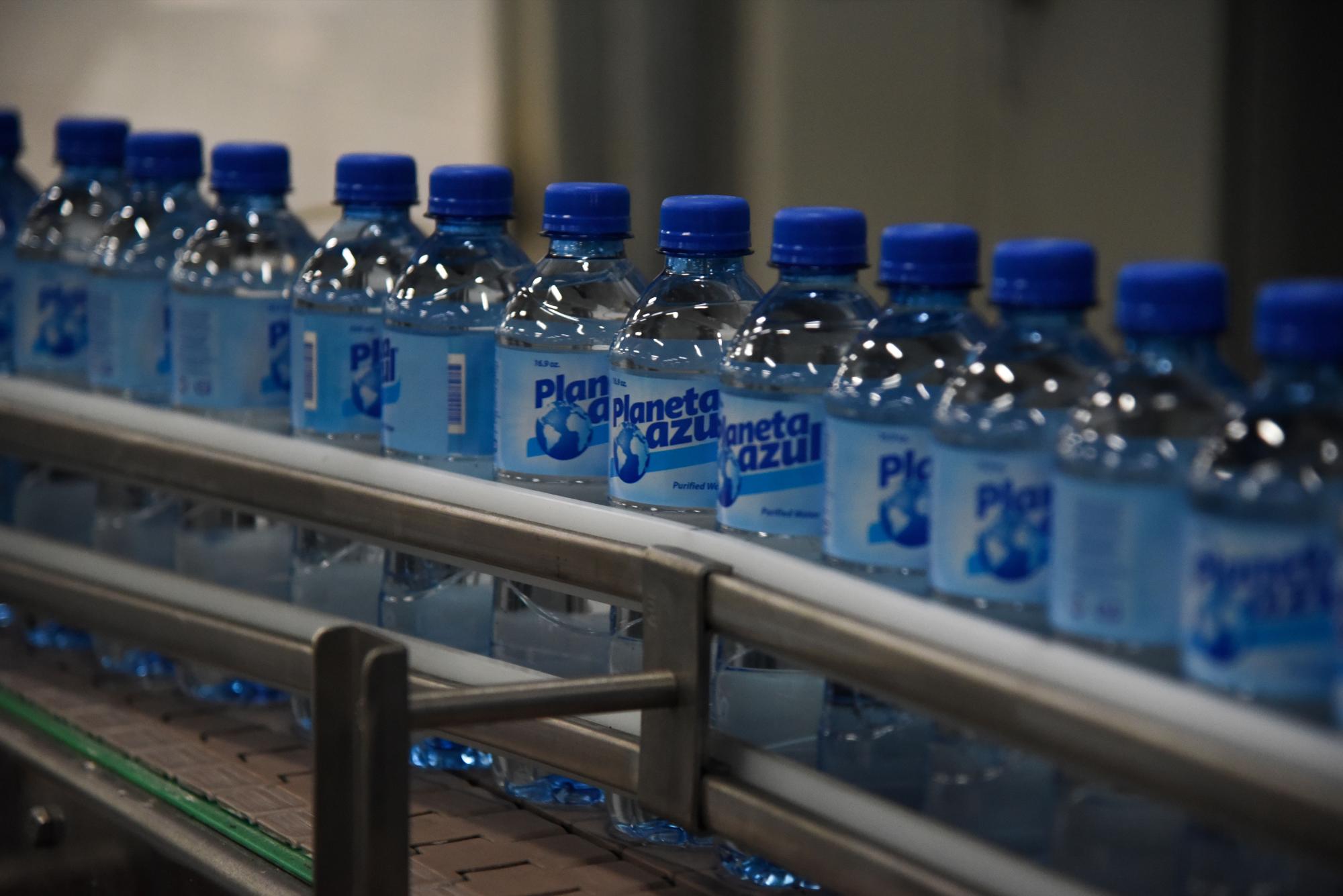 Las botellas de agua luego de pasar por la máquina que les coloca la tapa y la etiqueta.