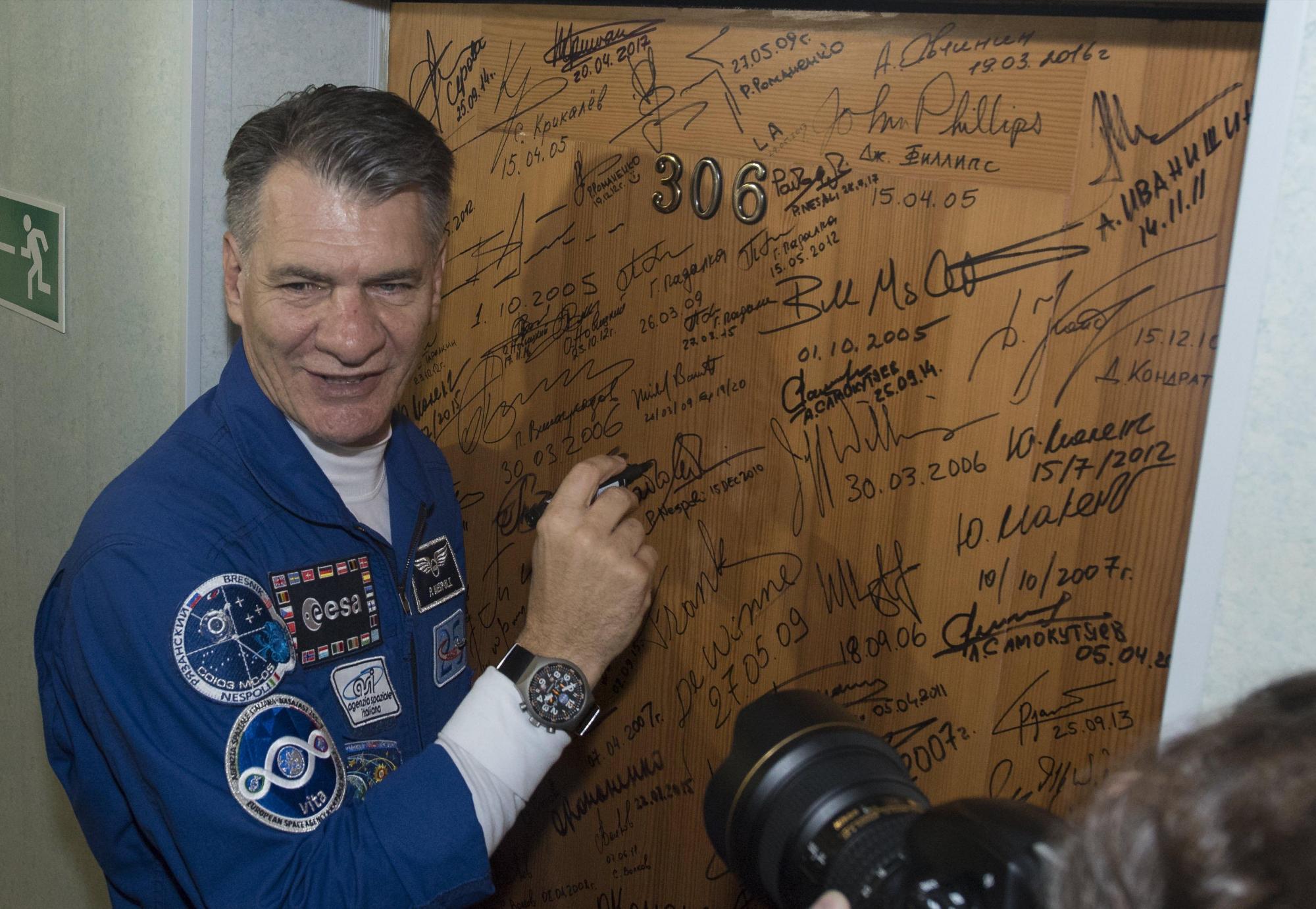 Fotografía cedida hoy, 28 de julio de 2017, por la NASA, que muestra al astronauta de la Expedición 52-53 Paolo Nespoli mientras firma la puerta del Hotel Cosmonaut.