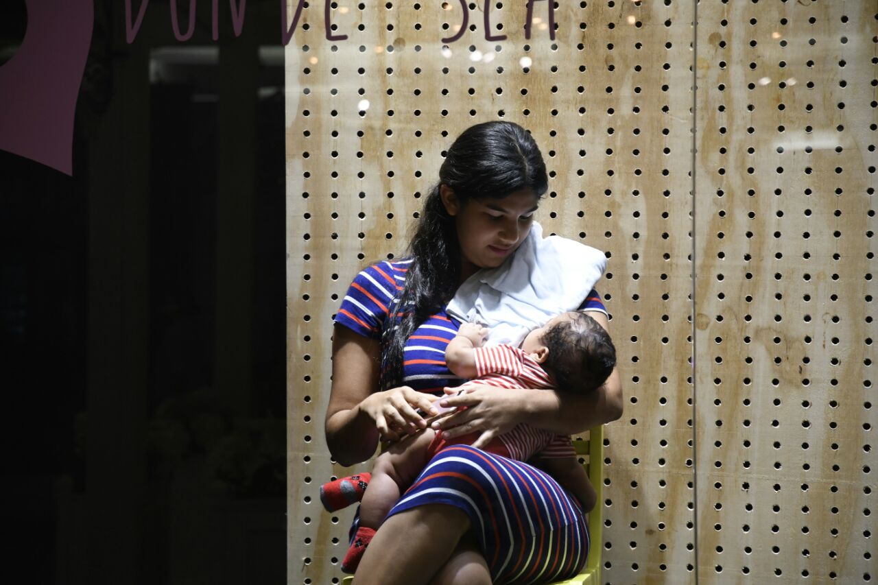 Madre amamanta a su hijo en una de las vitrinas de la plaza comercial 360. 