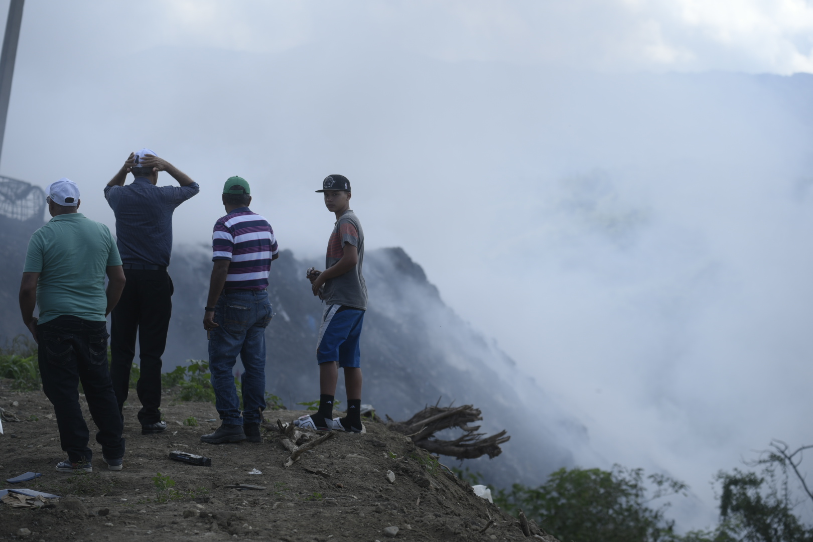 Personas observan la humareda que dejó el vertedero incendiado.