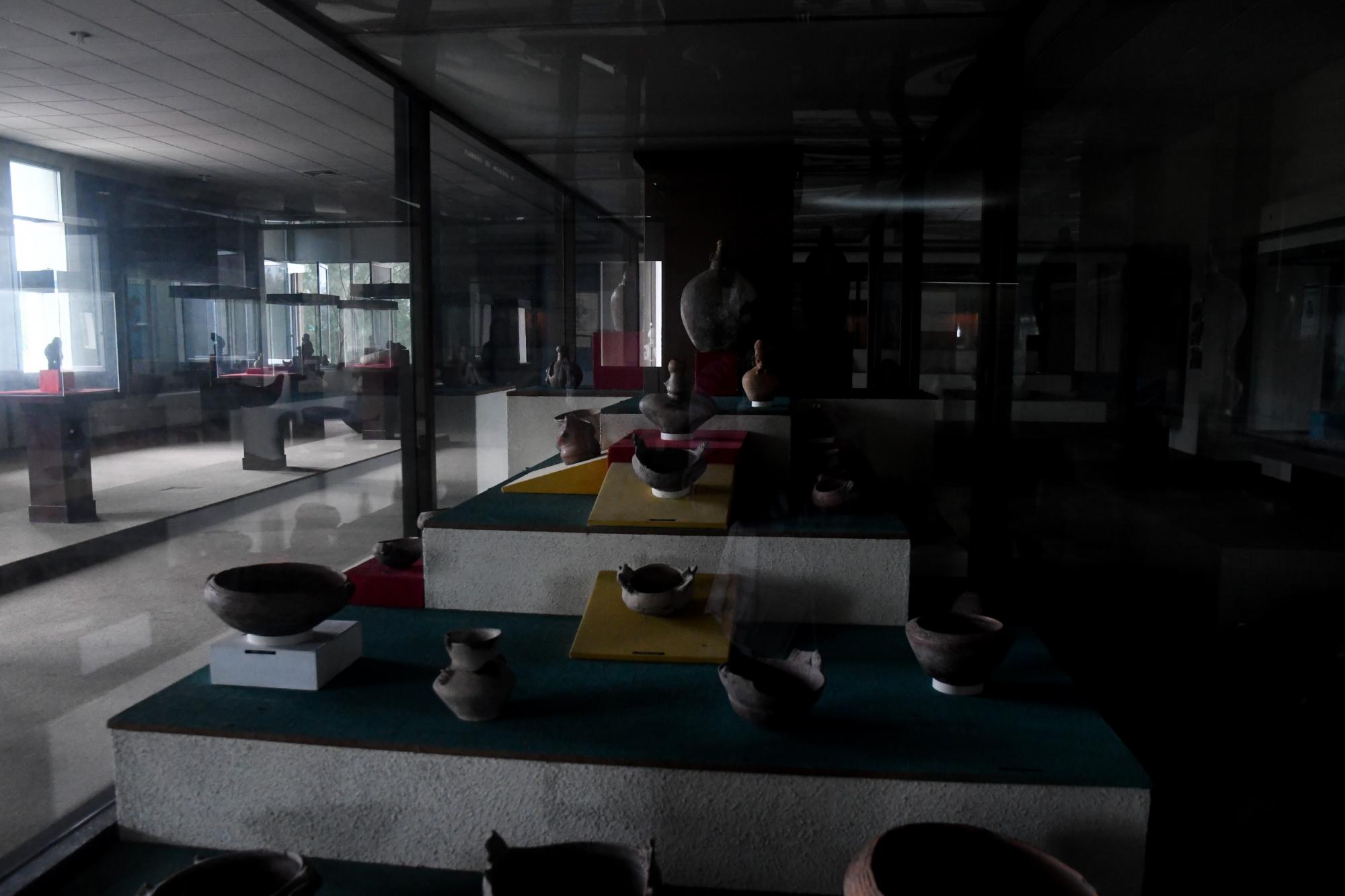 Piezas de la cultura taína exhibidas en una sala sin iluminación.