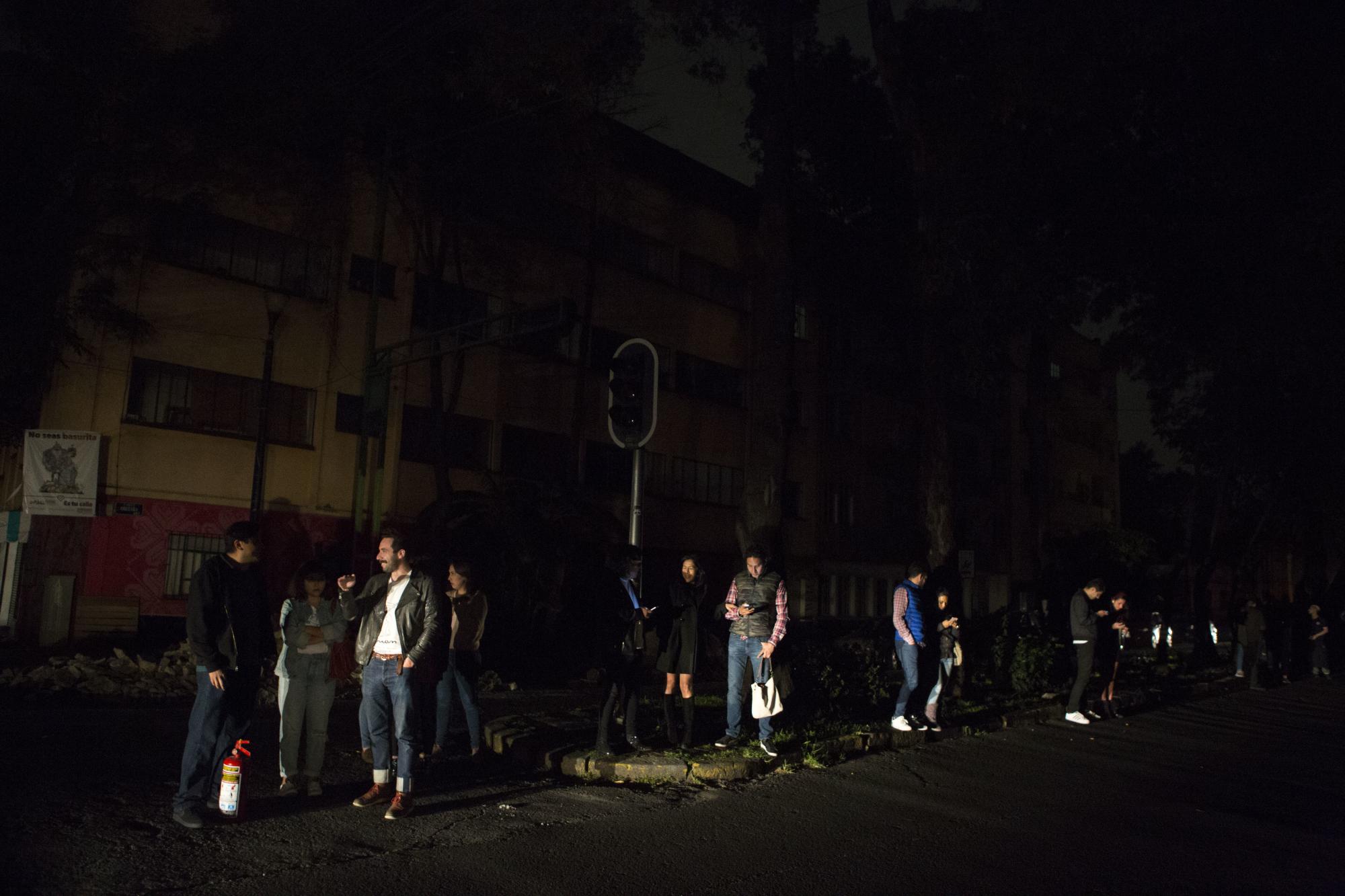 Gente evacuada de bares por un terremoto espera de pie en la calle en el barrio de La Roma, en Ciudad de México, donde algunas zonas se quedaron sin electricidad tras el sismo.