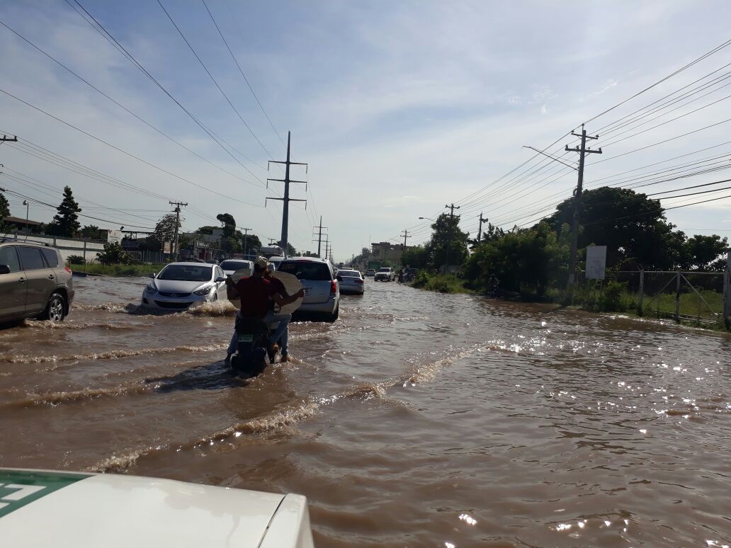 Imagen de la inundación que provocó la rotura de un tubo de agua potable en la autopista San Isidro, casi esquina Charles de Gaulle, lo que causó que se agravara también los tapones por esa zona de Santo Domingo Este.